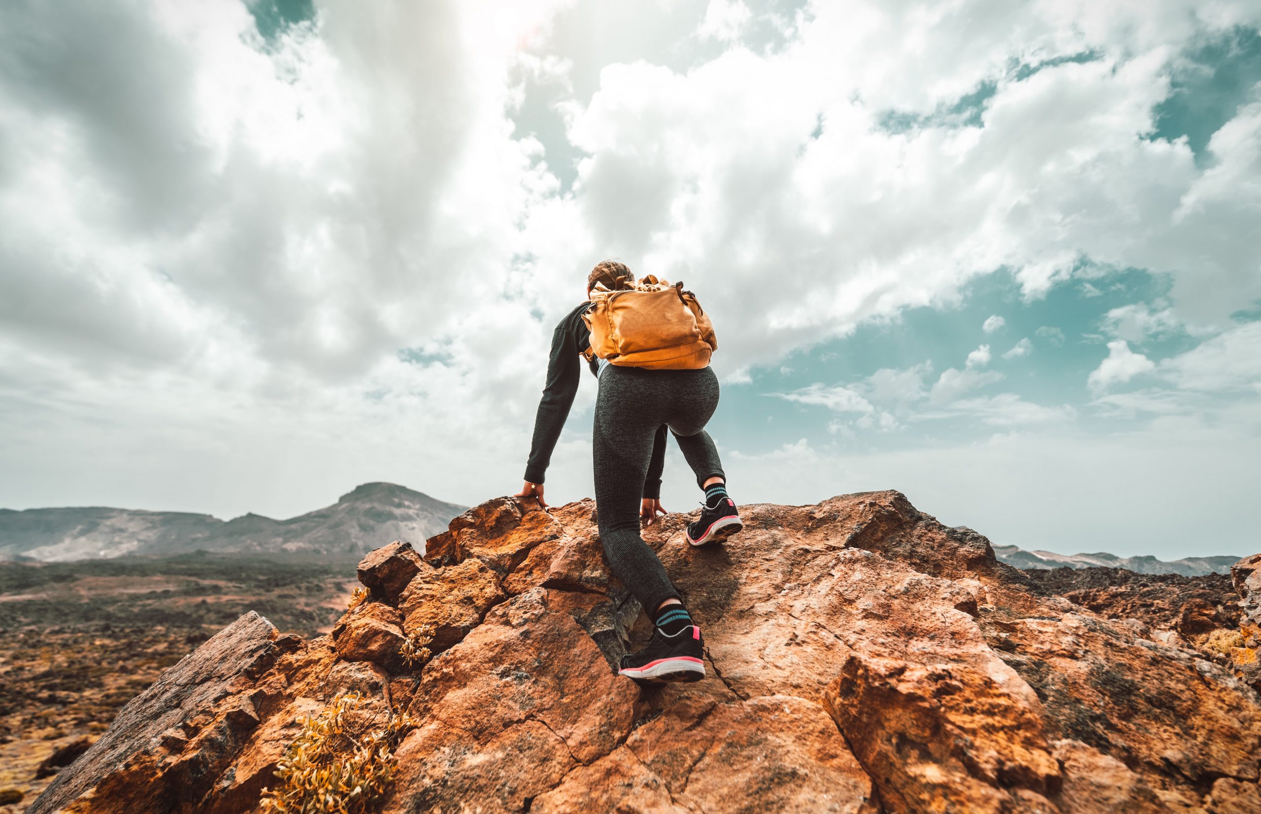 Wanderin mit Rucksack blickt von einem Berg in die Ferne